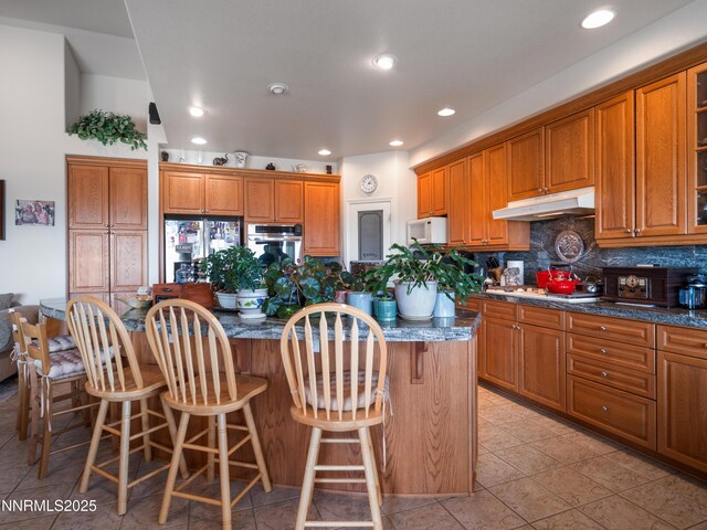 1037 Haystack Dr, Carson City, NV 89705 - kitchen with appliances with stainless steel finishes, under cabinet range hood, a center island, brown cabinets, and recessed lighting