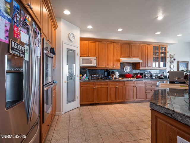 1037 Haystack Dr, Carson City, NV 89705 - kitchen with stainless steel appliances, brown cabinets, decorative backsplash, a sink, and under cabinet range hood