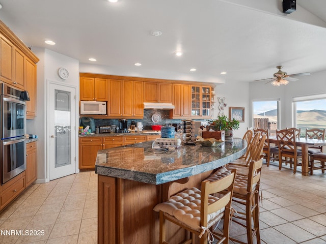 1037 Haystack Dr, Carson City, NV 89705 - kitchen with double oven, white microwave, under cabinet range hood, light tile patterned floors, and recessed lighting