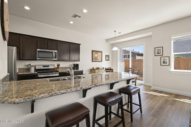910 Cranfield Ct, Reno, NV 89506 - kitchen featuring stainless steel appliances, a sink, dark brown cabinets, dark wood-type flooring, and a kitchen breakfast bar