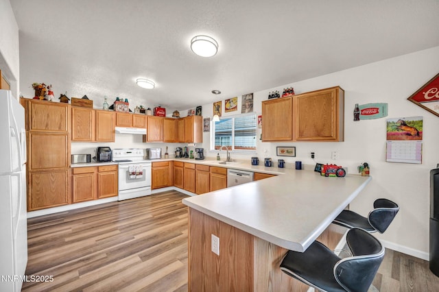 17533 Javalina Ct, Reno, NV 89508 - kitchen featuring white appliances, a peninsula, a sink, under cabinet range hood, and light countertops