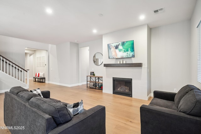 15058 Iron River Dr, Reno, NV 89521 - living room with stairs, light wood finished floors, a glass covered fireplace, recessed lighting, and baseboards