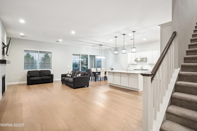 15058 Iron River Dr, Reno, NV 89521 - living area featuring stairs, recessed lighting, light wood-style flooring, a fireplace, and baseboards