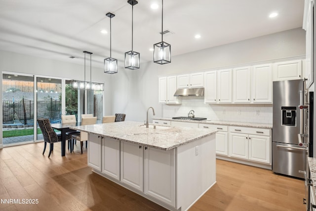 15058 Iron River Dr, Reno, NV 89521 - kitchen with appliances with stainless steel finishes, a sink, under cabinet range hood, tasteful backsplash, and light wood-style flooring