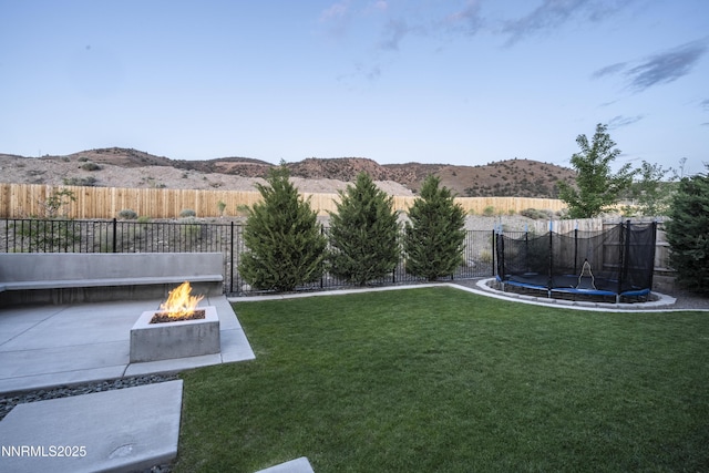 15058 Iron River Dr, Reno, NV 89521 - view of yard featuring an outdoor fire pit, a trampoline, a mountain view, and a patio area