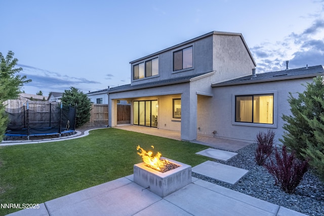 15058 Iron River Dr, Reno, NV 89521 - rear view of house with a fire pit, a patio, a trampoline, and stucco siding