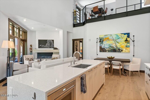 33 Beach Club Dr Unit 506, Stateline, NV 89449 - kitchen featuring a high ceiling, light wood-style floors, light brown cabinetry, a center island with sink, and light stone counters