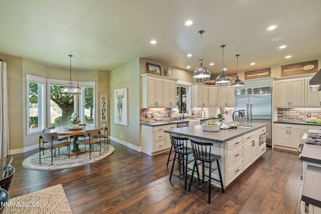 1020 N Cantlon Ln, Reno, NV 89521 - kitchen with tasteful backsplash, recessed lighting, a kitchen breakfast bar, a kitchen island with sink, and baseboards