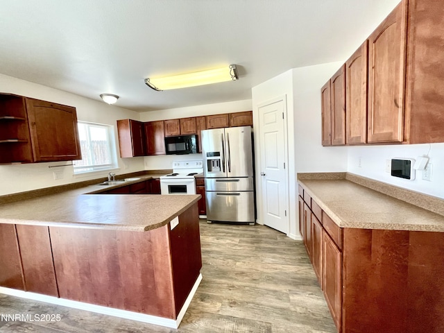935 Lonnie Ln, Winnemucca, NV 89445 - kitchen with black microwave, stainless steel fridge with ice dispenser, white electric range oven, a peninsula, and light wood-type flooring