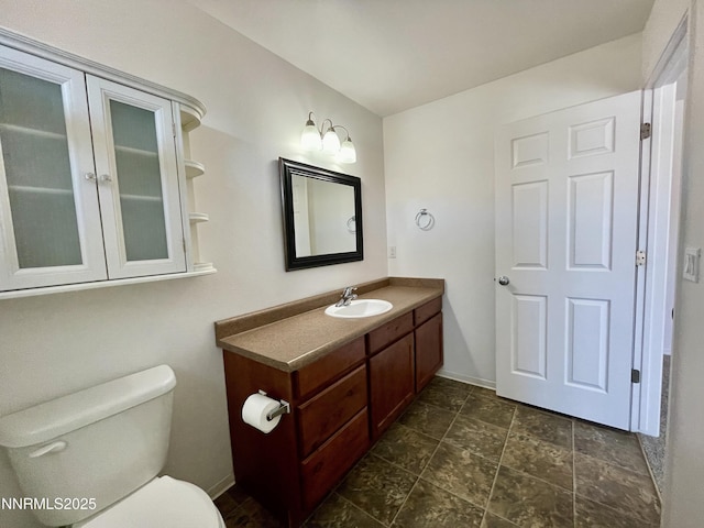 935 Lonnie Ln, Winnemucca, NV 89445 - bathroom featuring vanity, toilet, baseboards, and stone finish floors