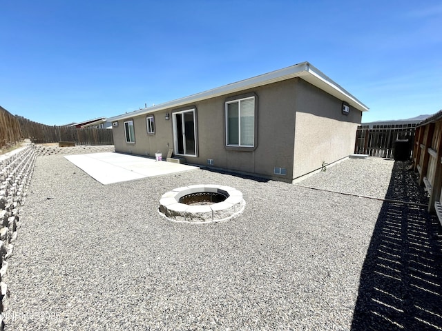 935 Lonnie Ln, Winnemucca, NV 89445 - back of house with a patio area, a fenced backyard, an outdoor fire pit, and stucco siding