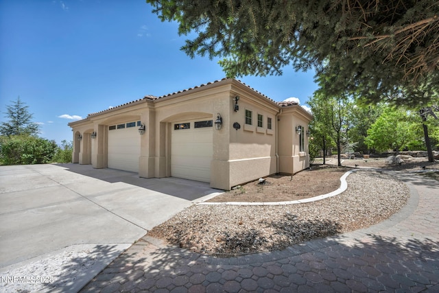 14210 Wild Quail Ct, Reno, NV 89511 - view of side of home featuring driveway, stucco siding, an attached garage, and a tile roof