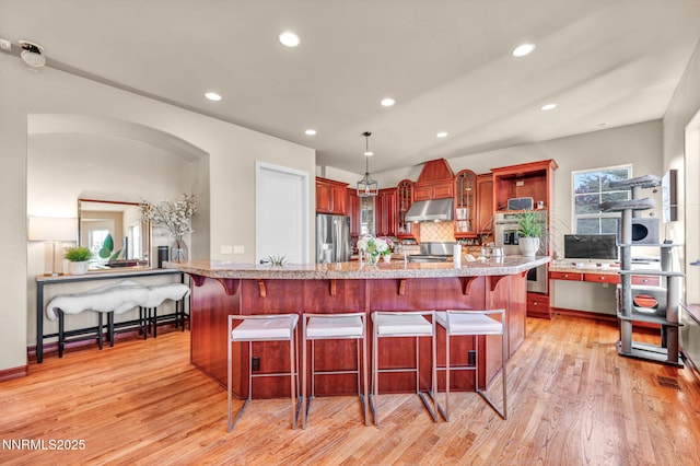 14210 Wild Quail Ct, Reno, NV 89511 - kitchen featuring stainless steel fridge with ice dispenser, under cabinet range hood, light wood finished floors, backsplash, and recessed lighting
