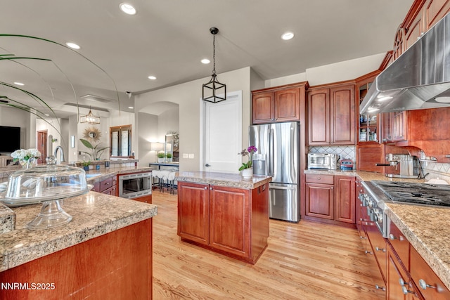 14210 Wild Quail Ct, Reno, NV 89511 - kitchen featuring appliances with stainless steel finishes, a large island, under cabinet range hood, light wood-type flooring, and light countertops