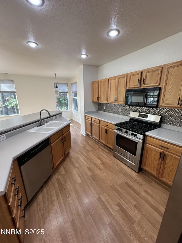 4748 Cedarhill Ln, Reno, NV 89519 - kitchen with stainless steel appliances, a sink, a textured ceiling, backsplash, and light wood-style floors