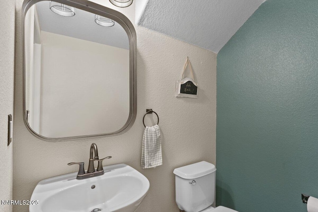 1955 Wind Ranch Rd Unit A, Reno, NV 89521 - bathroom featuring a sink, toilet, lofted ceiling, and a textured wall