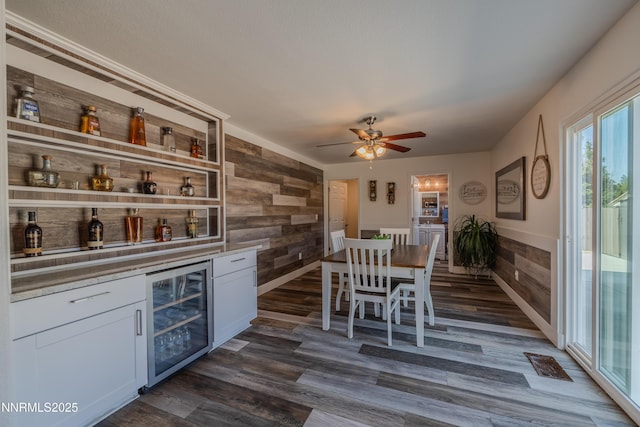 18105 Pasado Ct, Reno, NV 89508 - dining area featuring wine cooler, a bar, wood walls, dark wood-style floors, and a ceiling fan