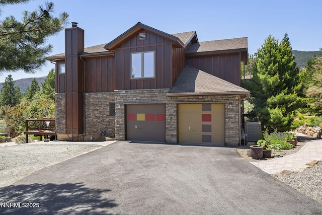 16460 Jefte Ct, Reno, NV 89511 - view of front of house featuring roof with shingles, driveway, a chimney, board and batten siding, and stone siding