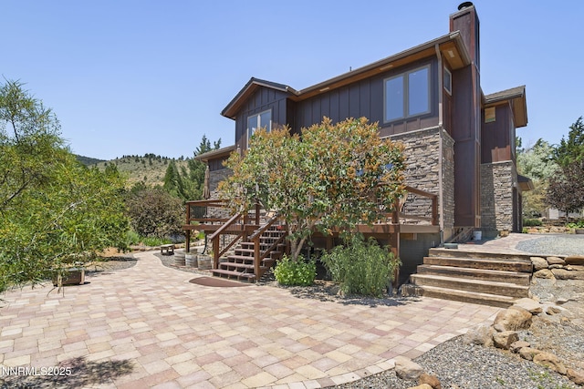 16460 Jefte Ct, Reno, NV 89511 - back of property with stairway, board and batten siding, a patio area, a deck, and a chimney