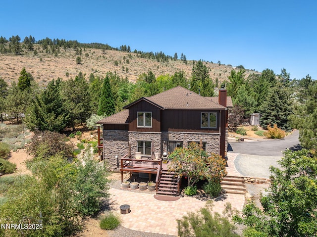 16460 Jefte Ct, Reno, NV 89511 - rear view of house with stone siding, a chimney, stairway, a wooden deck, and a shingled roof