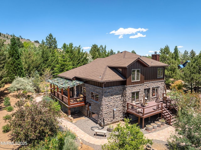 16460 Jefte Ct, Reno, NV 89511 - rear view of property featuring stone siding, board and batten siding, a deck, a chimney, and a shingled roof