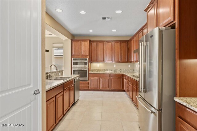 1080 S University Park Loop, Reno, NV 89512 - kitchen with stainless steel appliances, a sink, light tile patterned floors, brown cabinets, and recessed lighting