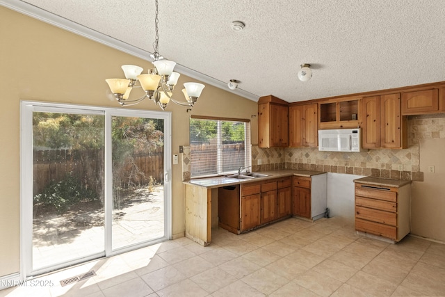 779 E York Way, Sparks, NV 89434 - kitchen featuring white microwave, a textured ceiling, ornamental molding, brown cabinetry, and lofted ceiling