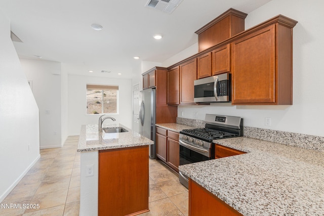 3002 Sterling Ridge Cir, Sparks, NV 89431 - kitchen with appliances with stainless steel finishes, a sink, a kitchen island with sink, light stone counters, and brown cabinetry