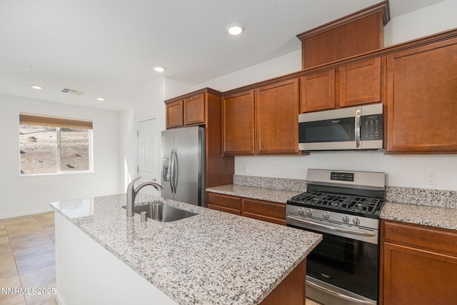 3002 Sterling Ridge Cir, Sparks, NV 89431 - kitchen with appliances with stainless steel finishes, a sink, an island with sink, light stone countertops, and brown cabinets