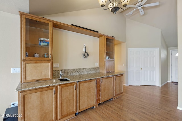 115 Stags Leap Cir, Spanish Springs, NV 89441 - kitchen featuring lofted ceiling, light wood-type flooring, light stone countertops, and glass insert cabinets