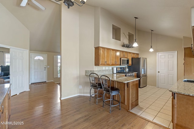 115 Stags Leap Cir, Spanish Springs, NV 89441 - kitchen featuring high vaulted ceiling, stainless steel appliances, brown cabinets, a breakfast bar area, and a peninsula