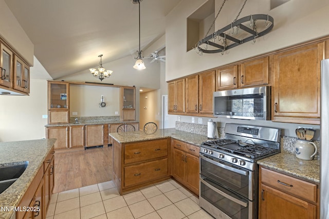 115 Stags Leap Cir, Spanish Springs, NV 89441 - kitchen with appliances with stainless steel finishes, a peninsula, a chandelier, lofted ceiling, and brown cabinets