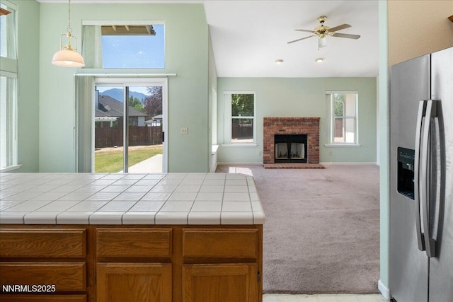 1290 Saddlehorn Ct, Minden, NV 89423 - kitchen featuring stainless steel fridge with ice dispenser, carpet flooring, tile counters, a brick fireplace, and ceiling fan
