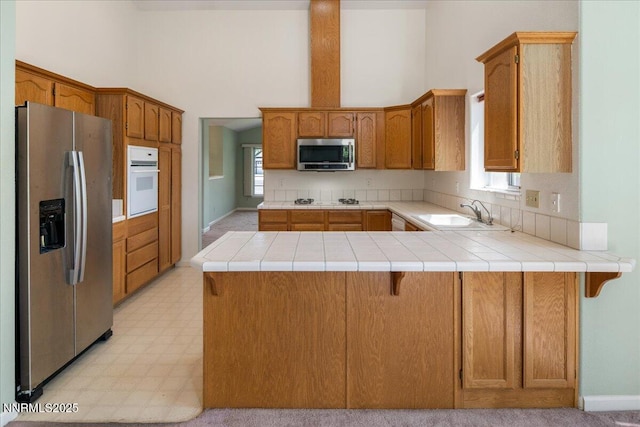 1290 Saddlehorn Ct, Minden, NV 89423 - kitchen featuring stainless steel appliances, a peninsula, a towering ceiling, light countertops, and light floors
