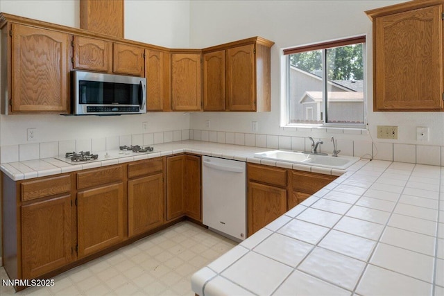1290 Saddlehorn Ct, Minden, NV 89423 - kitchen with white appliances, brown cabinetry, tile counters, and light flooring