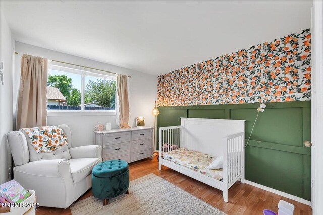 809 Glen Valley Dr, Sparks, NV 89434 - bedroom with wood finished floors, a crib, wallpapered walls, an accent wall, and a wainscoted wall