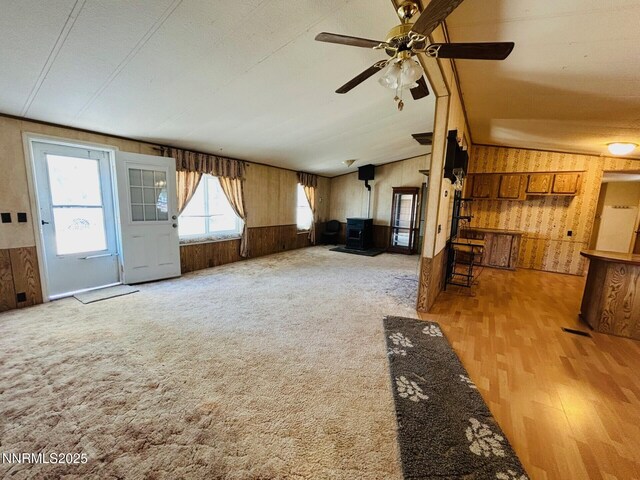 6480 Teal Dr, Fallon, NV 89406 - unfurnished living room with wooden walls, wood finished floors, a wood stove, ceiling fan, and vaulted ceiling