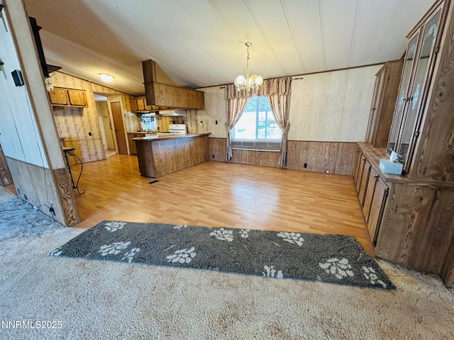 6480 Teal Dr, Fallon, NV 89406 - kitchen featuring wood walls, a chandelier, a peninsula, light wood-style flooring, and vaulted ceiling