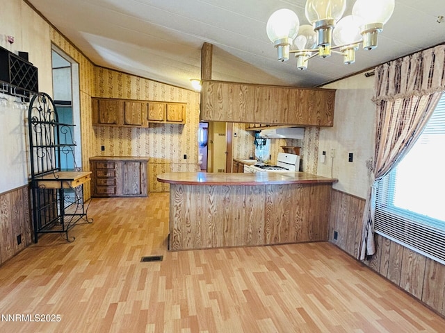 6480 Teal Dr, Fallon, NV 89406 - kitchen featuring range, brown cabinets, light wood-style floors, vaulted ceiling, and a chandelier
