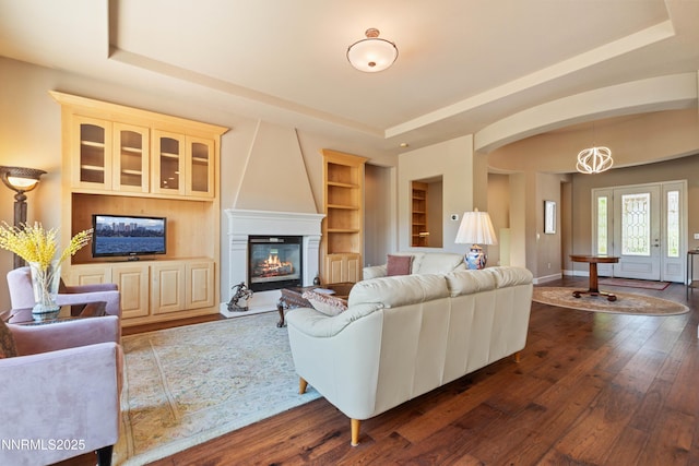 7601 Autumn Ridge Cir, Reno, NV 89523 - living area featuring a tray ceiling, dark wood-style floors, a large fireplace, and built in shelves