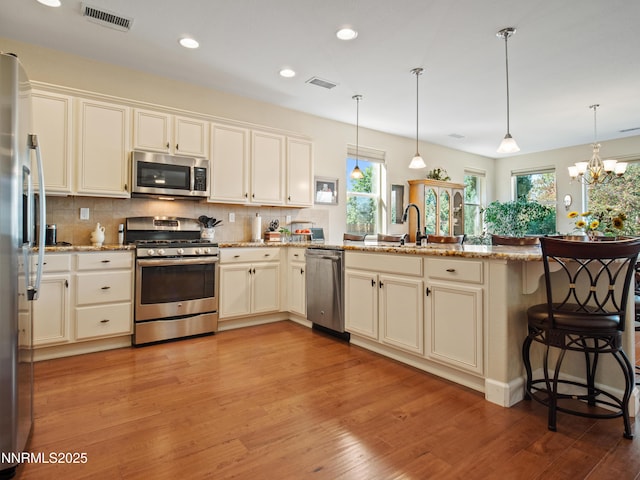 1221 Lasso Ln, Gardnerville, NV 89410 - kitchen with appliances with stainless steel finishes, a peninsula, light wood-style flooring, decorative backsplash, and recessed lighting
