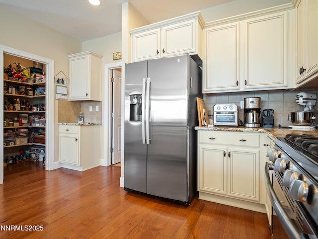 1221 Lasso Ln, Gardnerville, NV 89410 - kitchen featuring appliances with stainless steel finishes, backsplash, light wood-type flooring, and light stone countertops