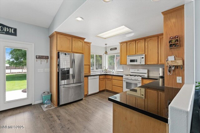 805 Samantha Cir, Fallon, NV 89406 - kitchen featuring white appliances, dark countertops, decorative backsplash, wood finished floors, and hanging light fixtures