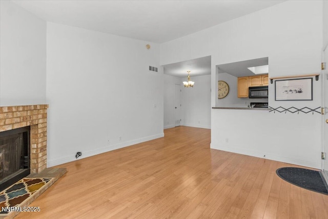 530 E Patriot Blvd Unit 128, Reno, NV 89511 - unfurnished living room with light wood-style floors, a chandelier, a brick fireplace, and baseboards