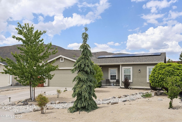 18573 Outpost Ct, Reno, NV 89508 - obstructed view of property featuring an attached garage, covered porch, stucco siding, roof with shingles, and solar panels