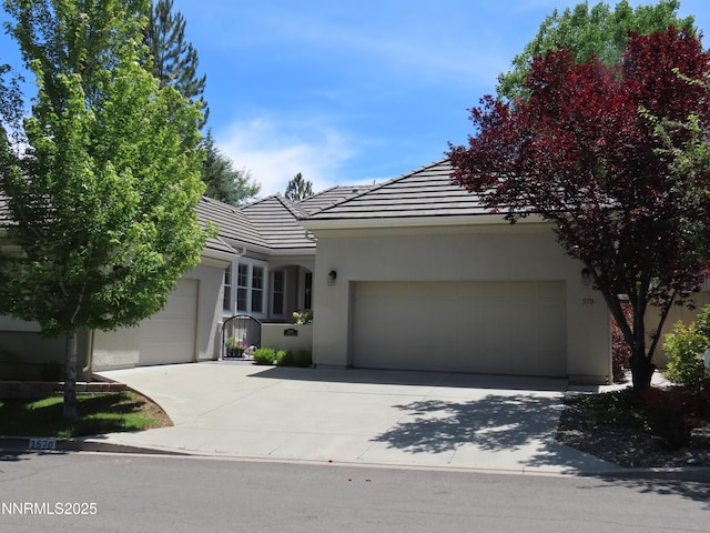 1570 Caughlin Creek Rd, Reno, NV 89519 - view of front facade featuring a tiled roof, an attached garage, stucco siding, and concrete driveway