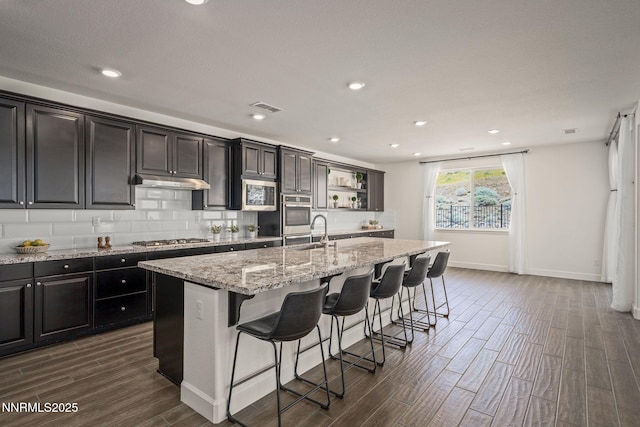 10450 Palladium Mine Dr, Reno, NV 89521 - kitchen featuring stainless steel appliances, dark wood-style floors, a center island with sink, a sink, and a breakfast bar area