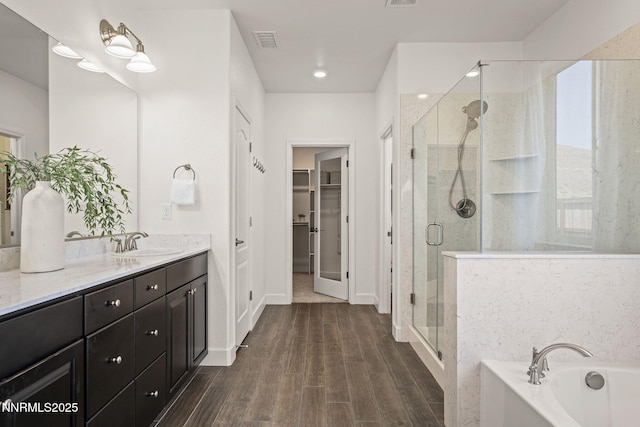 10450 Palladium Mine Dr, Reno, NV 89521 - bathroom with vanity, a shower stall, a garden tub, and wood finished floors