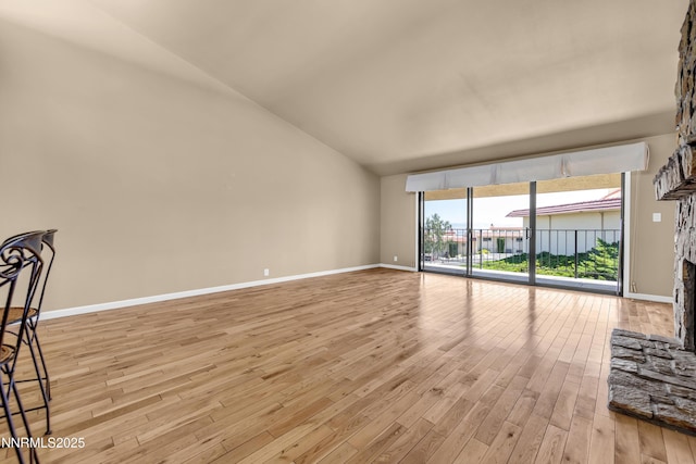 3467 Skyline Blvd, Reno, NV 89509 - empty room with light wood-style flooring, baseboards, a fireplace, vaulted ceiling, and expansive windows