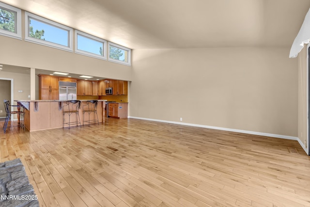 3467 Skyline Blvd, Reno, NV 89509 - unfurnished living room with a towering ceiling, light wood-style floors, and baseboards